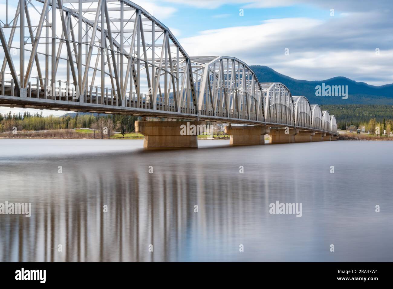 Grande ponte in acciaio costruito dall'uomo che attraversa la baia di Nisutlin nella cittadina di Teslin che scorre verso il fiume Yukon nel Canada settentrionale durante la primavera Foto Stock