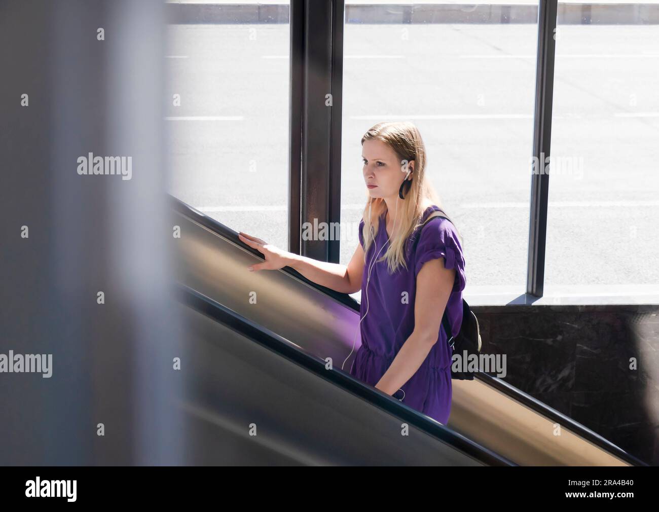 Belgrado, Serbia - 15 giugno 2022: Giovane donna in abito viola che sale sulla scala mobile della metropolitana, in una giornata di sole Foto Stock
