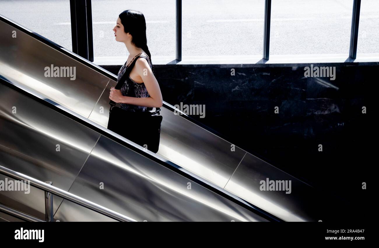 Belgrado, Serbia - 15 giugno 2022: Una giovane donna sale sulla scala mobile della metropolitana, in una giornata di sole Foto Stock