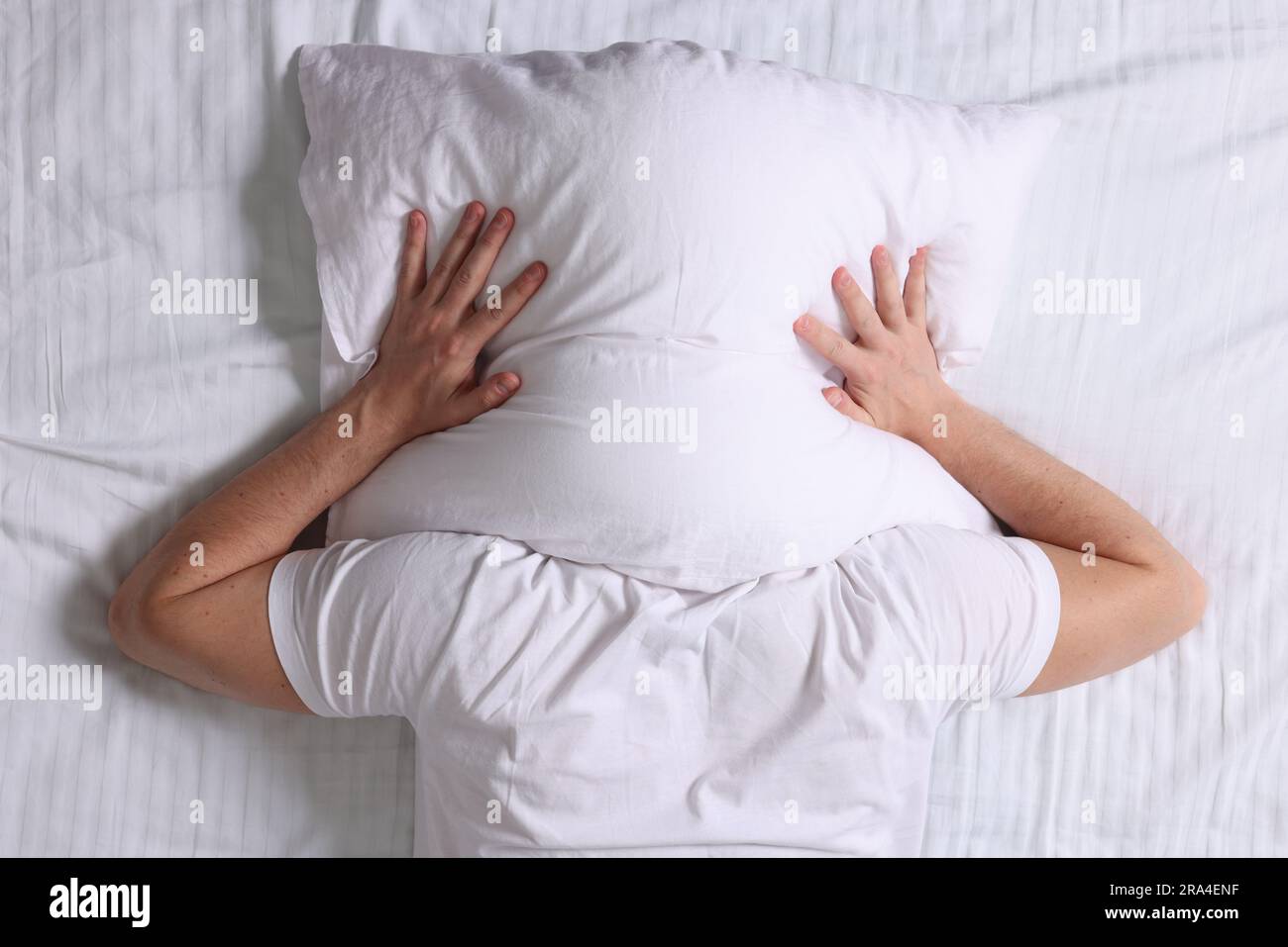 Uomo che si copre la testa con un cuscino nel letto, vista dall