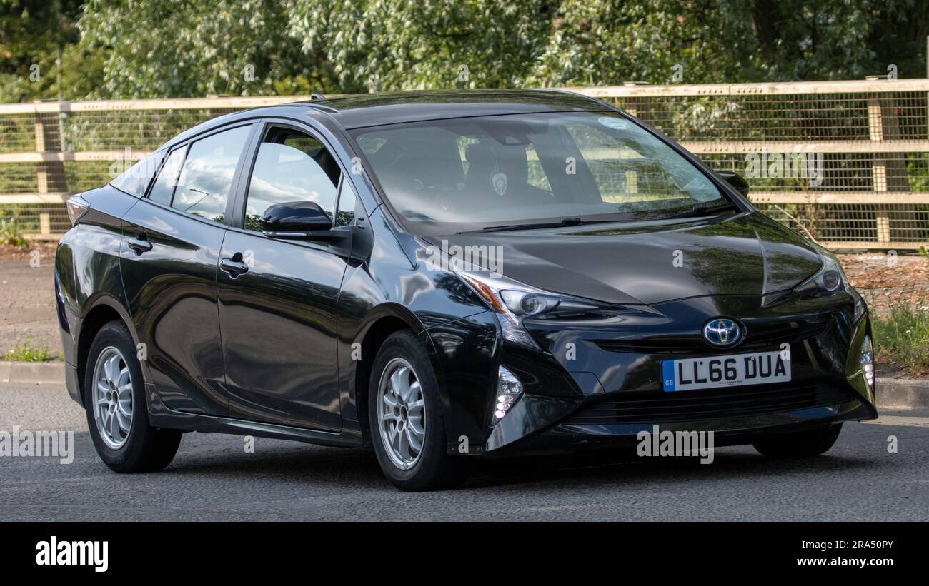 Milton Keynes, Regno Unito - 24 giugno 2023. 2016 auto elettrica ibrida TOYOTA PRIUS nera che viaggia su una strada di campagna inglese Foto Stock