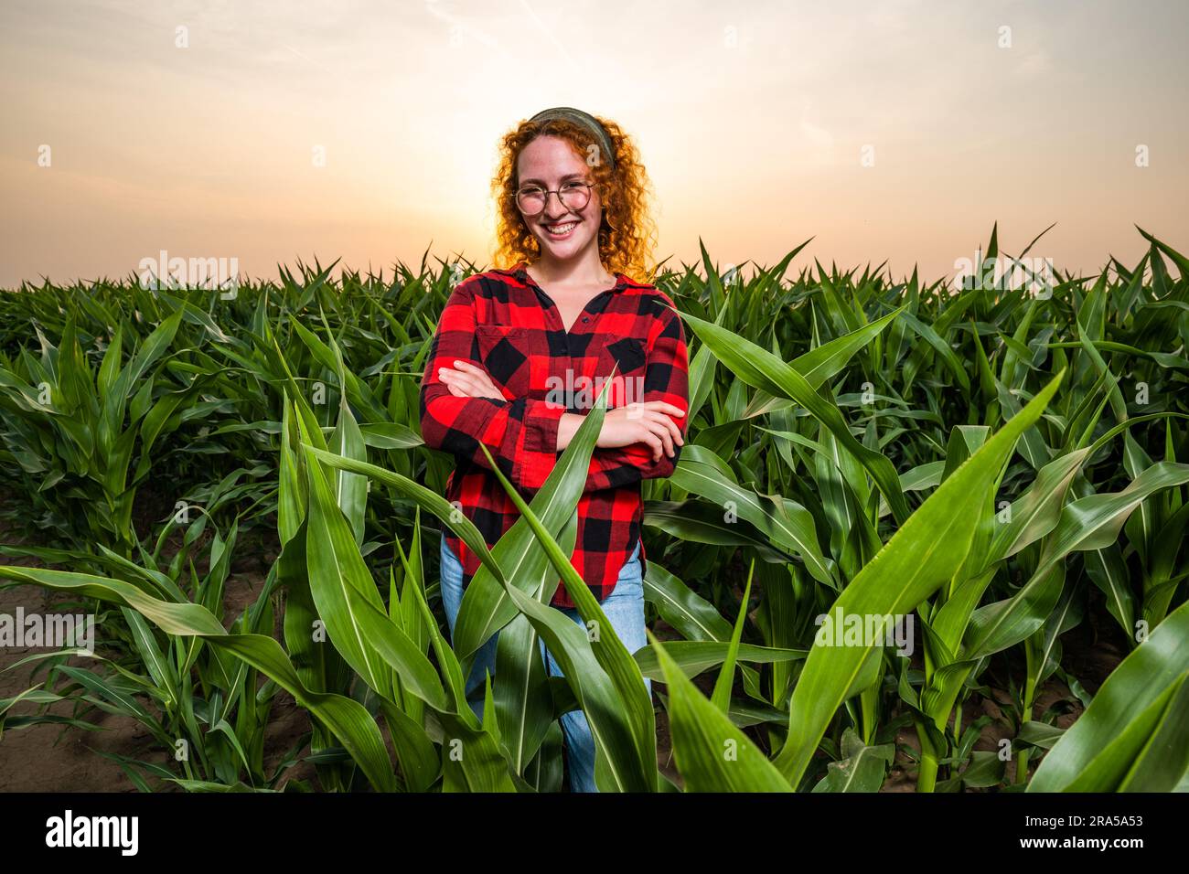 Ritratto di una contadina che sta coltivando mais. È soddisfatta dei buoni progressi delle piante. Occupazione agricola. Foto Stock