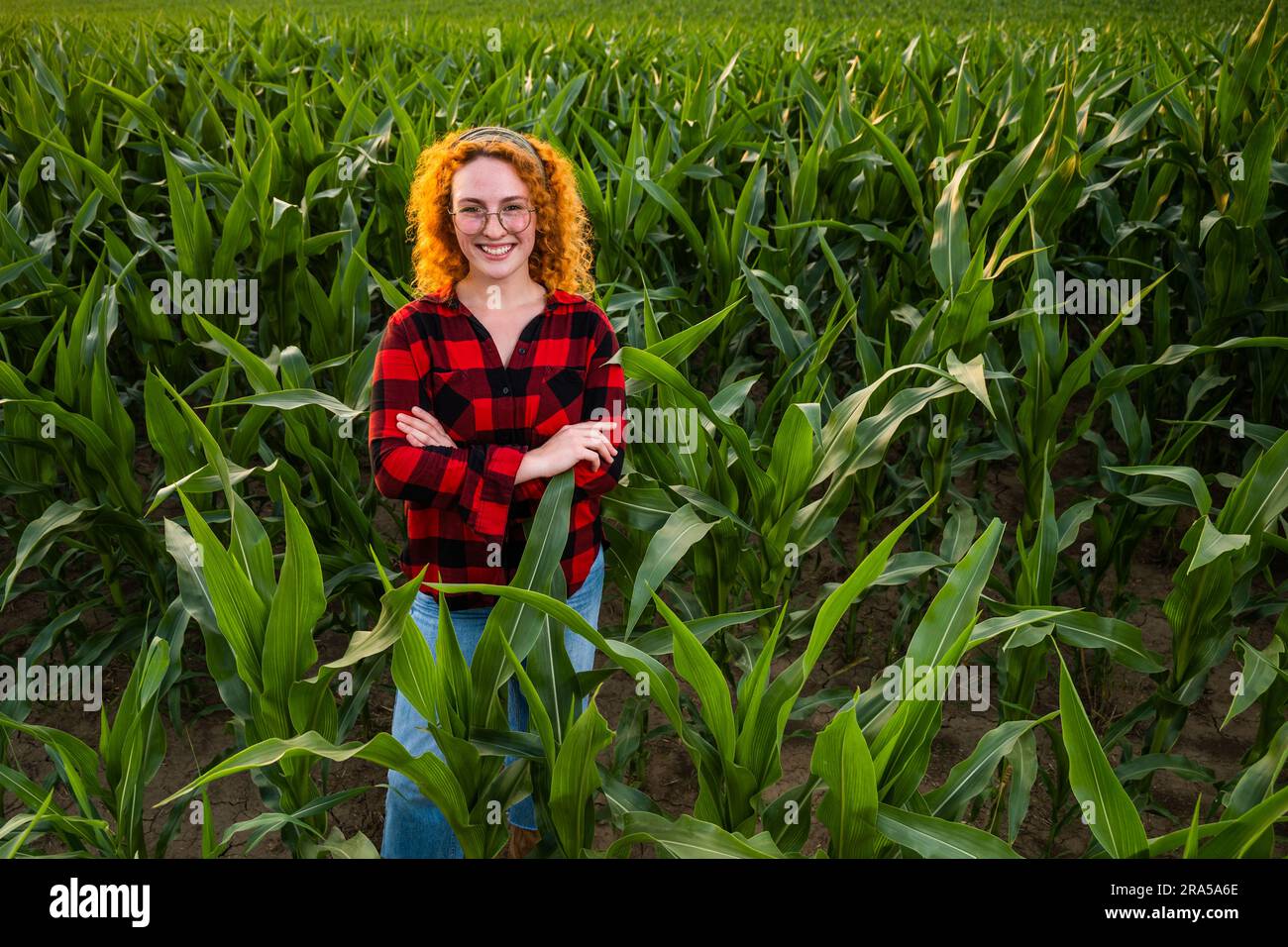 Ritratto di una contadina che sta coltivando mais. È soddisfatta dei buoni progressi delle piante. Occupazione agricola. Foto Stock