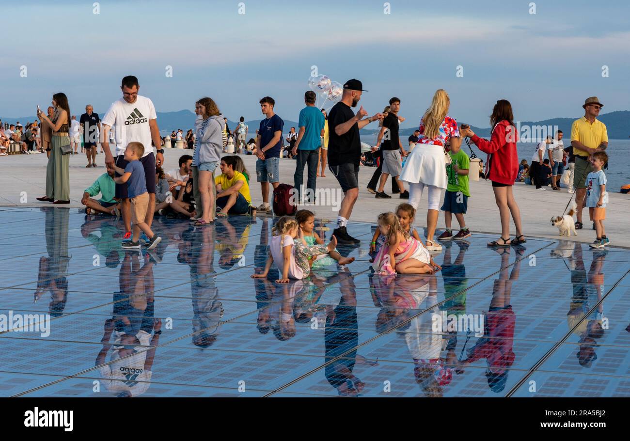 Gente che cammina e siede sul Monumento al sole (noto anche come saluto al sole) al sole di Zara, Croazia Foto Stock