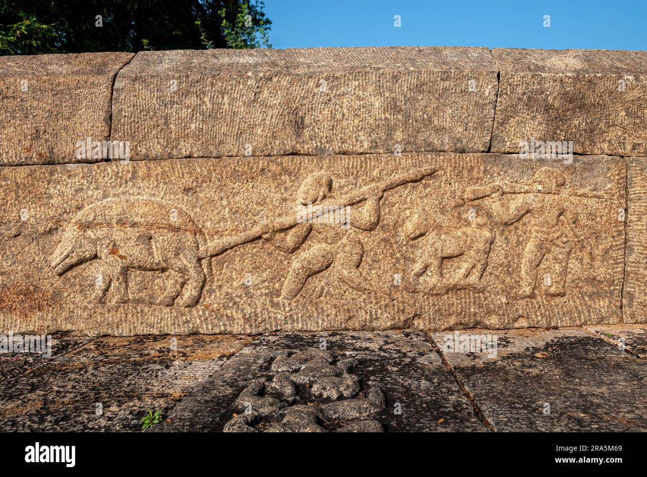 Un uomo che uccide un maiale, sculture in bassorilievo sul muro del parapetto del carro armato cinese Oorani vicino a Thiruvannamalai Tiruvannamalai, Tamil Nadu, Sud Foto Stock