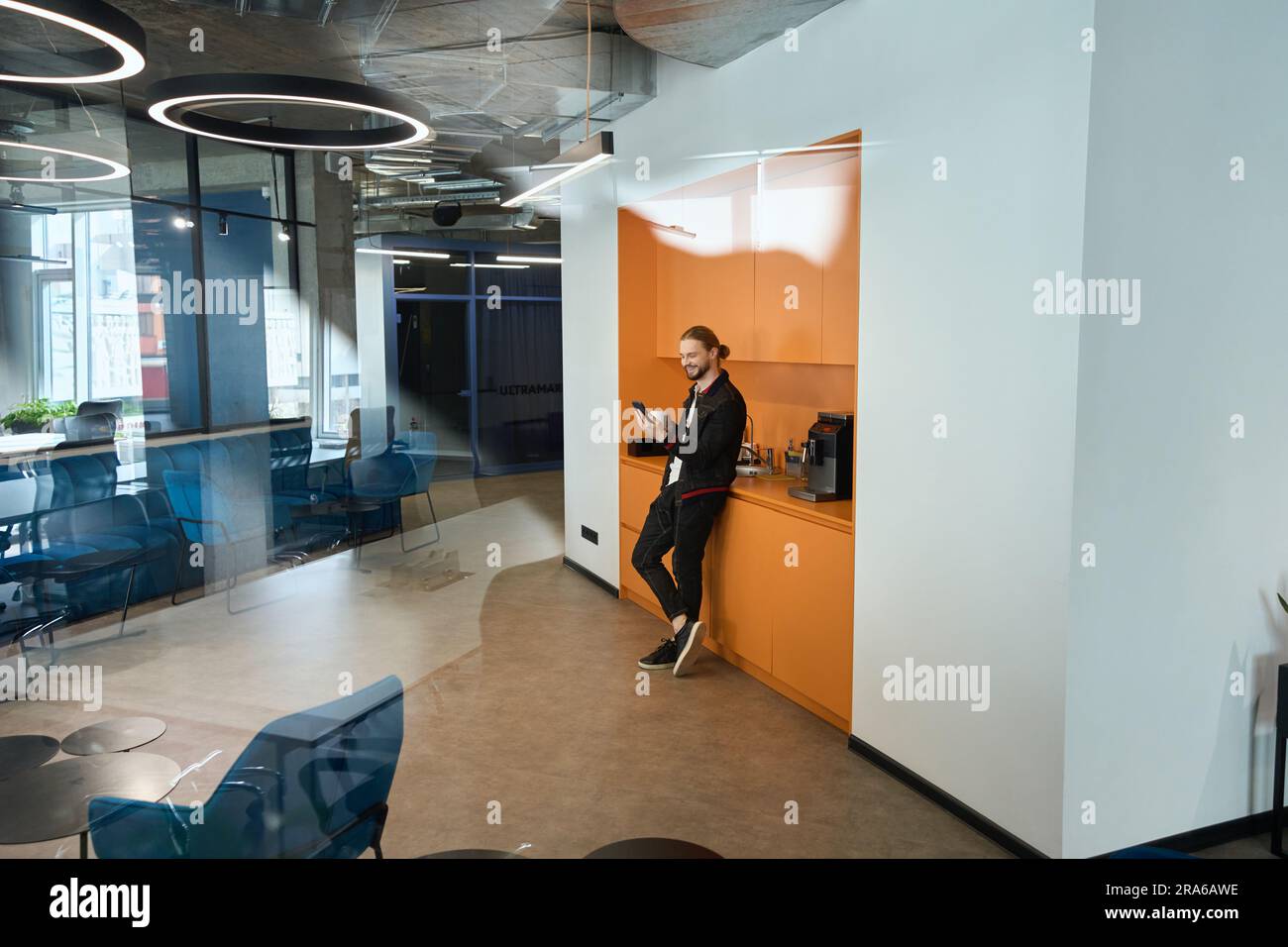 L'uomo barbuto si trova nella zona cucina nello spazio di coworking Foto Stock