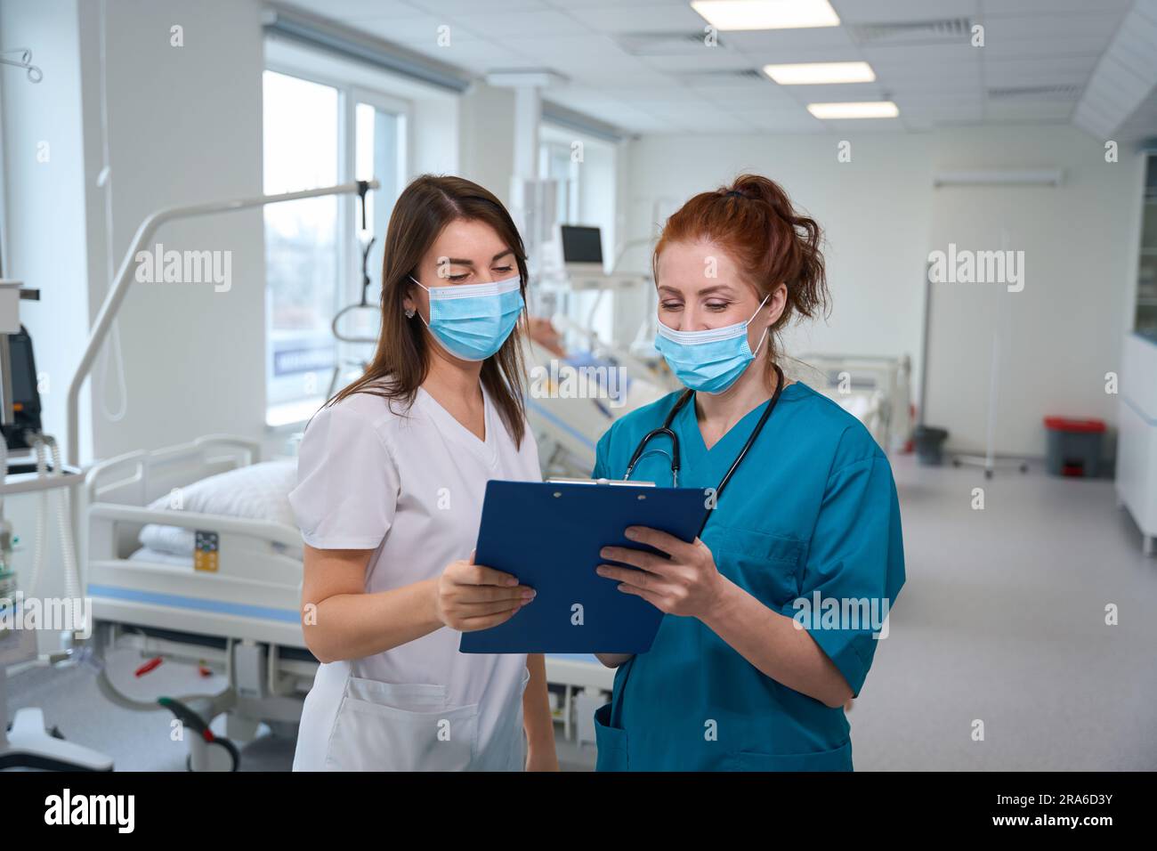 Medici femminili con appunti che parlano tra loro in clinica Foto Stock