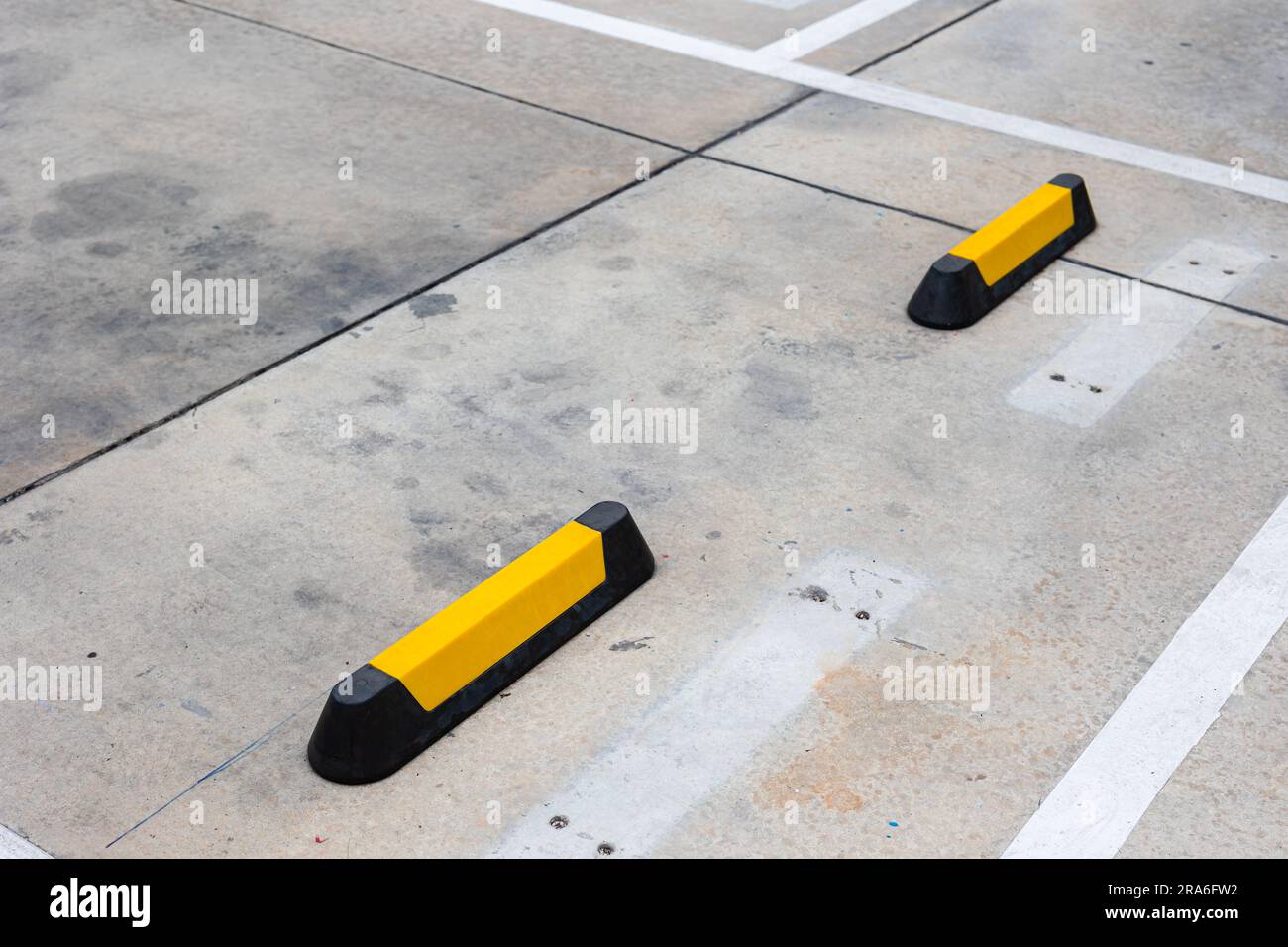 Blocco stradale in gomma per parcheggi, finecorsa per ruote con strisce riflettenti gialle per parcheggi. Foto Stock