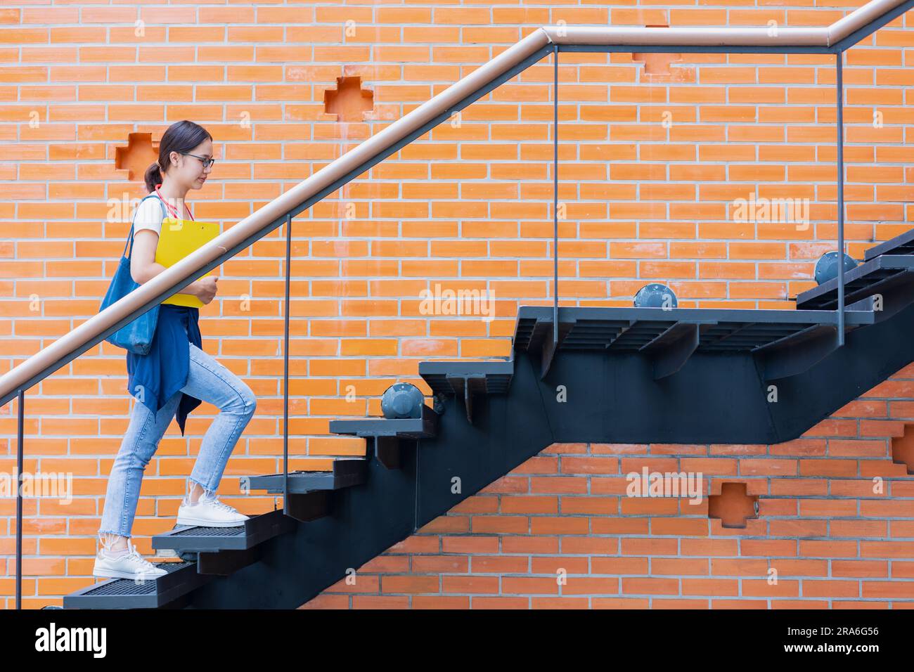 Gli studenti universitari camminano salgono le scale nel campus scolastico per innalzare il concetto di donna intelligente di maggior successo. Foto Stock