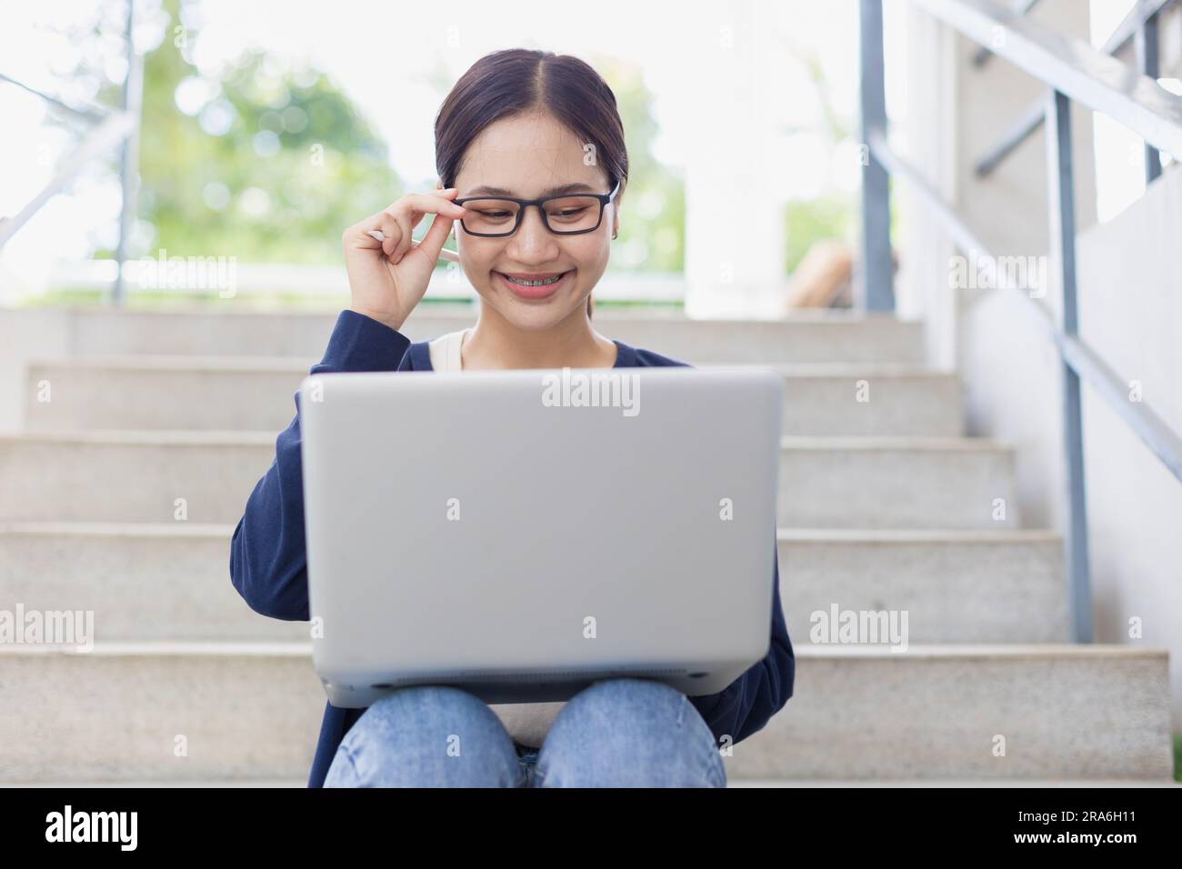 Adolescente universitaria felice sorridente ama usare il notebook per imparare l'istruzione nel campus scolastico. Foto Stock