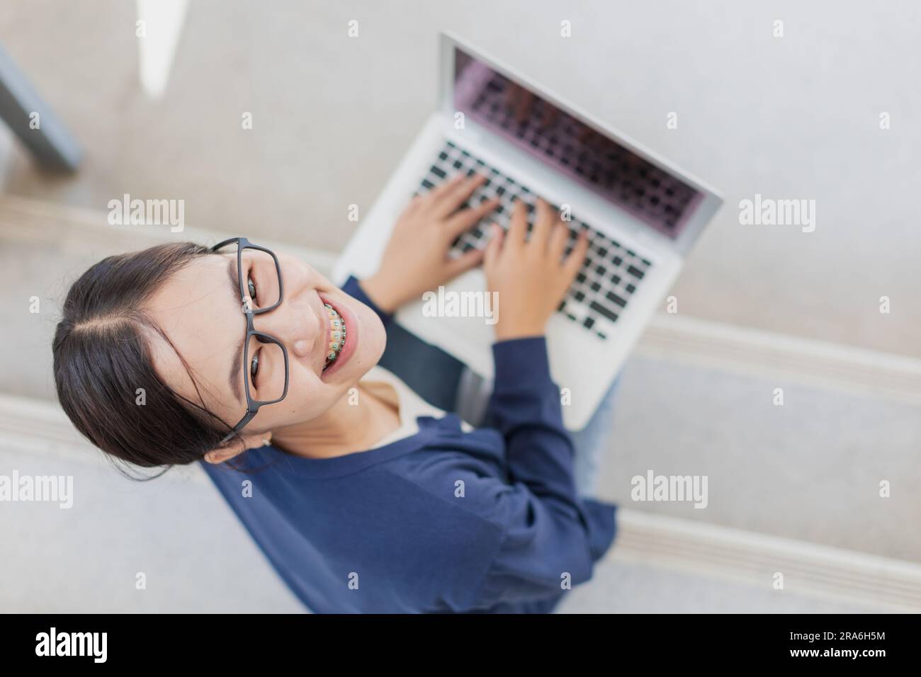 Adolescente universitaria felice sorridente ama usare il notebook per imparare l'istruzione nel campus scolastico. Foto Stock