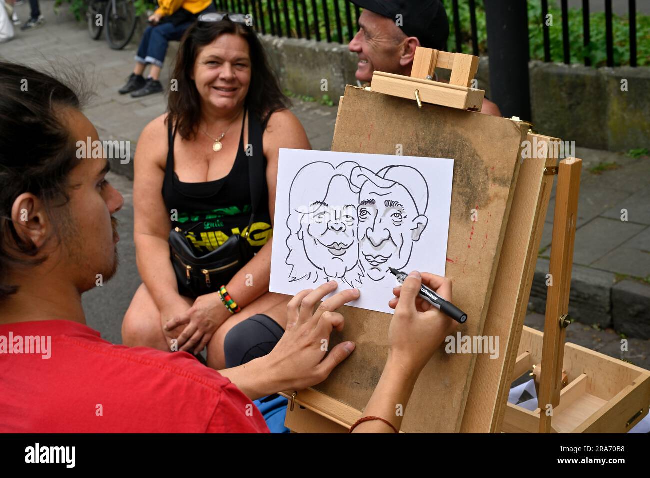 St Paul's Caribbean Carnival 2023, Bristol, Inghilterra, Regno Unito, 1 luglio 2023. St Pauls, Bristol. Artista che disegna una caricatura di due visitatori del carnevale Foto Stock