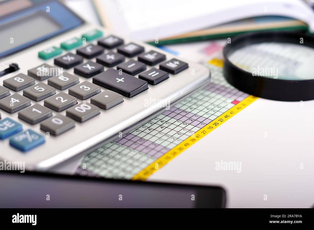 Tabella finanziaria con la calcolatrice e lente di ingrandimento Foto Stock