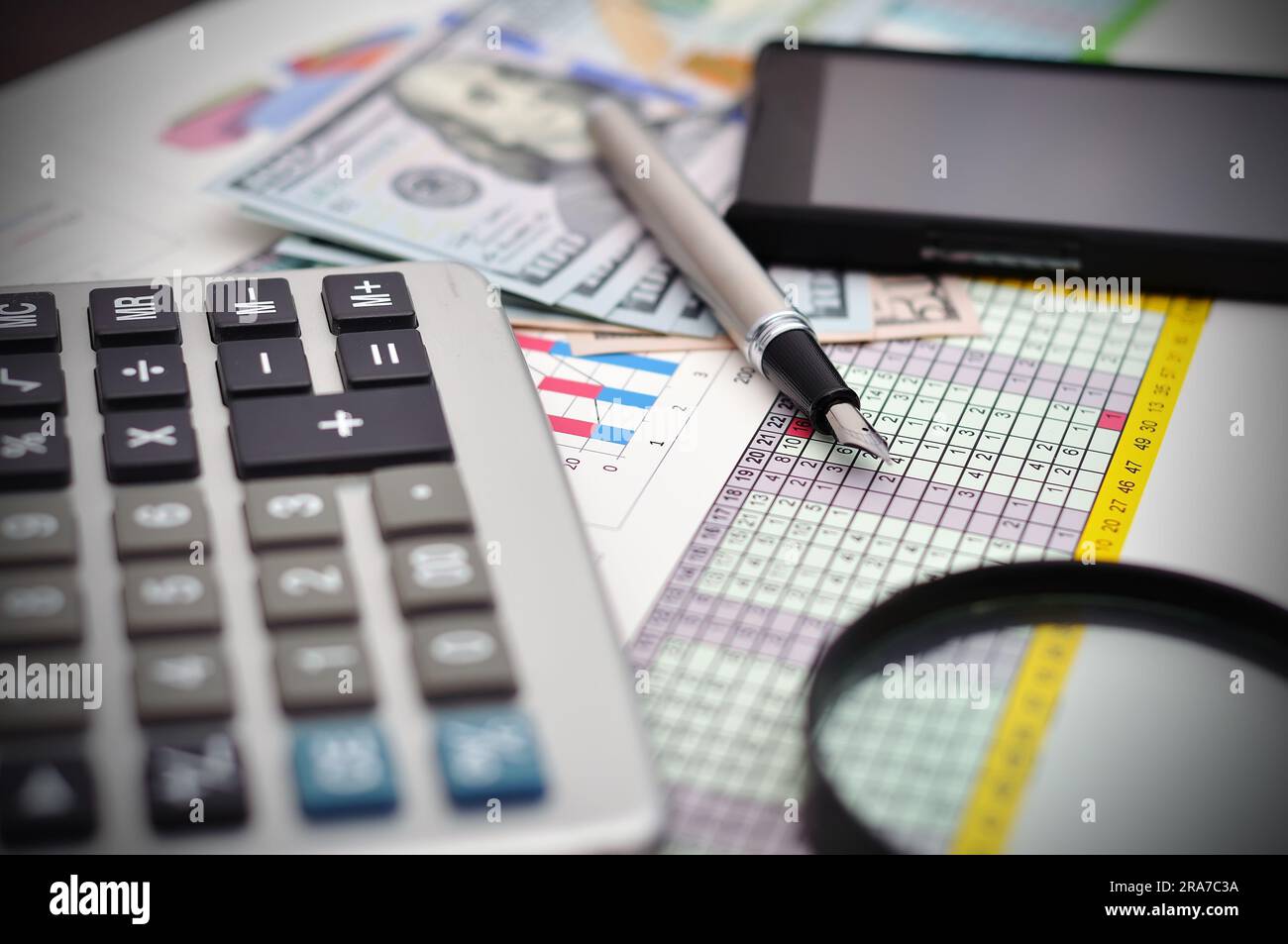 calcolatrice, telefono, denaro e penna stilografica sul tavolo Foto Stock