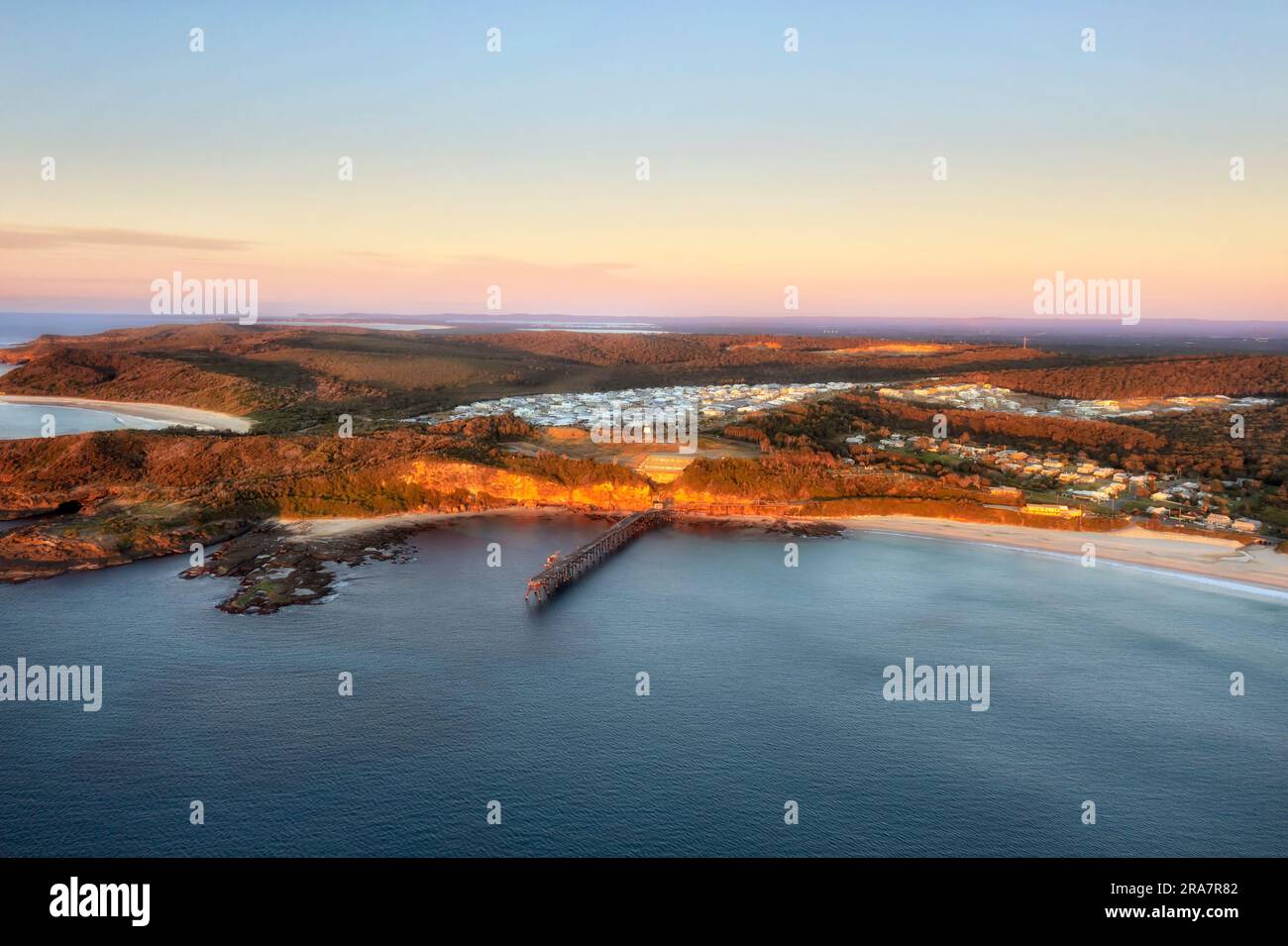 Middle Camp Beach nella cittadina della baia di Catherine Hill sulla costa australiana del Pacifico con il molo storico e il paesaggio aereo dell'alba. Foto Stock