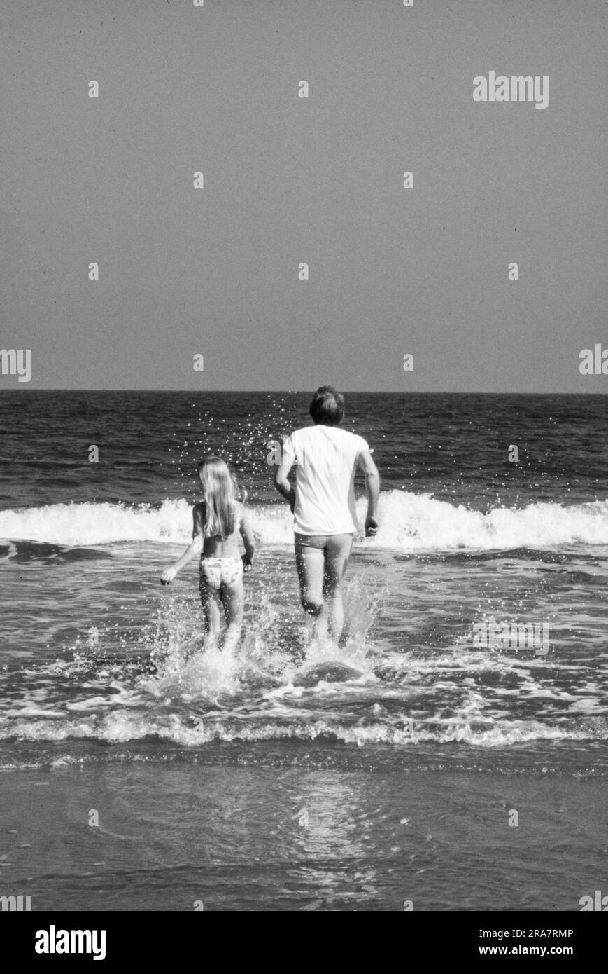 Il presidente Jimmy Carter e la figlia Amy Carter corrono nel surf a Sea Island, Georgia, mentre sono in vacanza. Foto di Bernard Gotfryd Foto Stock