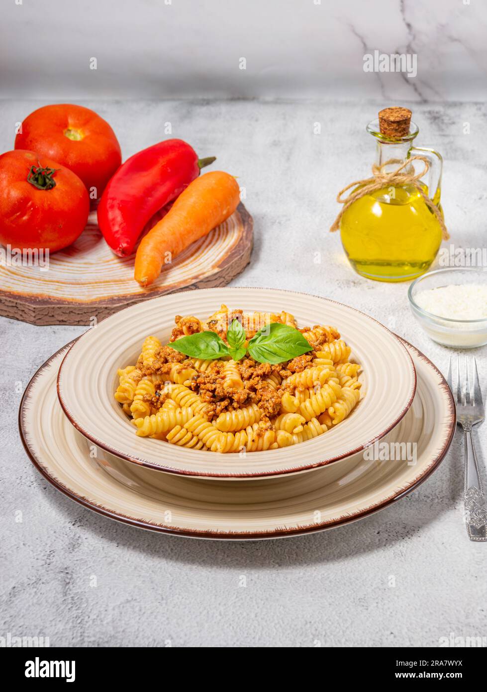 Fusilli con carne macinata, salsa di pomodoro, formaggio e basilico Foto Stock