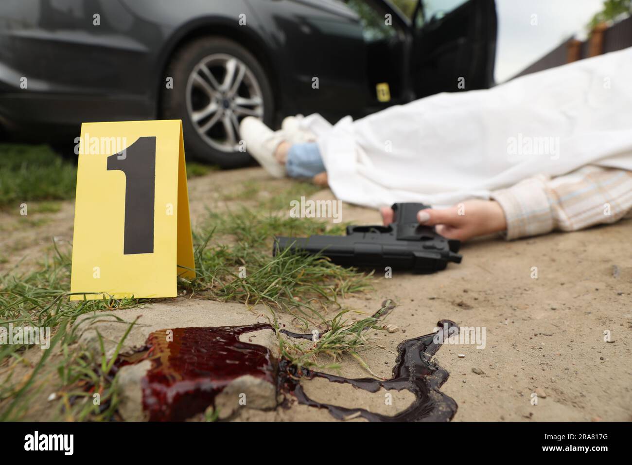 Marcatori della scena del crimine, corpo di donna morta e pistola all'aperto, concentrazione selettiva Foto Stock