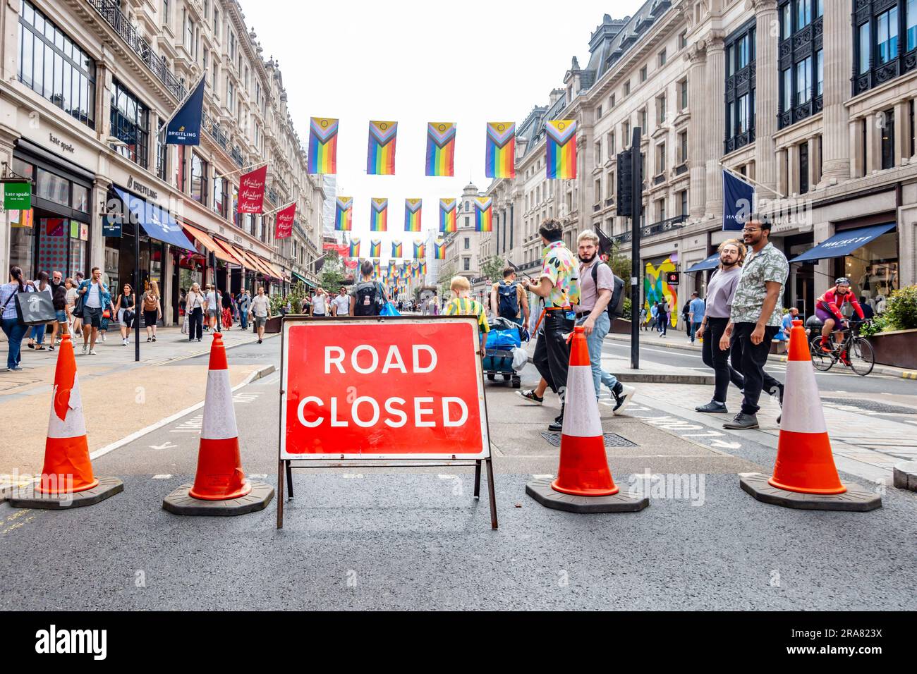 Regent Street è chiusa per l'annuale evento London Pride con un cartello rosso e coni stradali che bloccano la strada. Bandiere colorate a mano in alto. Foto Stock