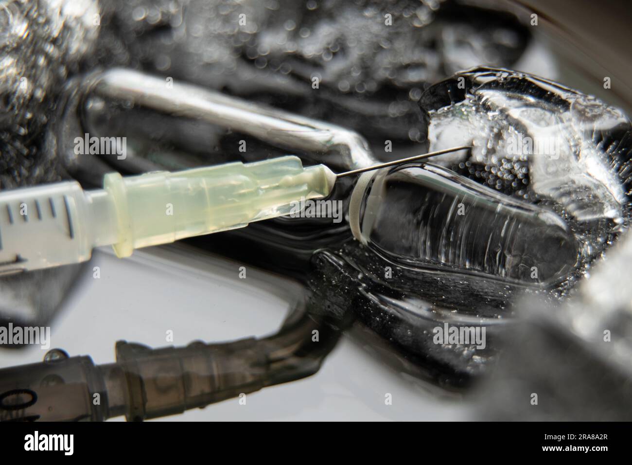 una siringa con un ago e una fiala con un vaccino in ghiaccio, vaccinazione di massa in un panda Foto Stock