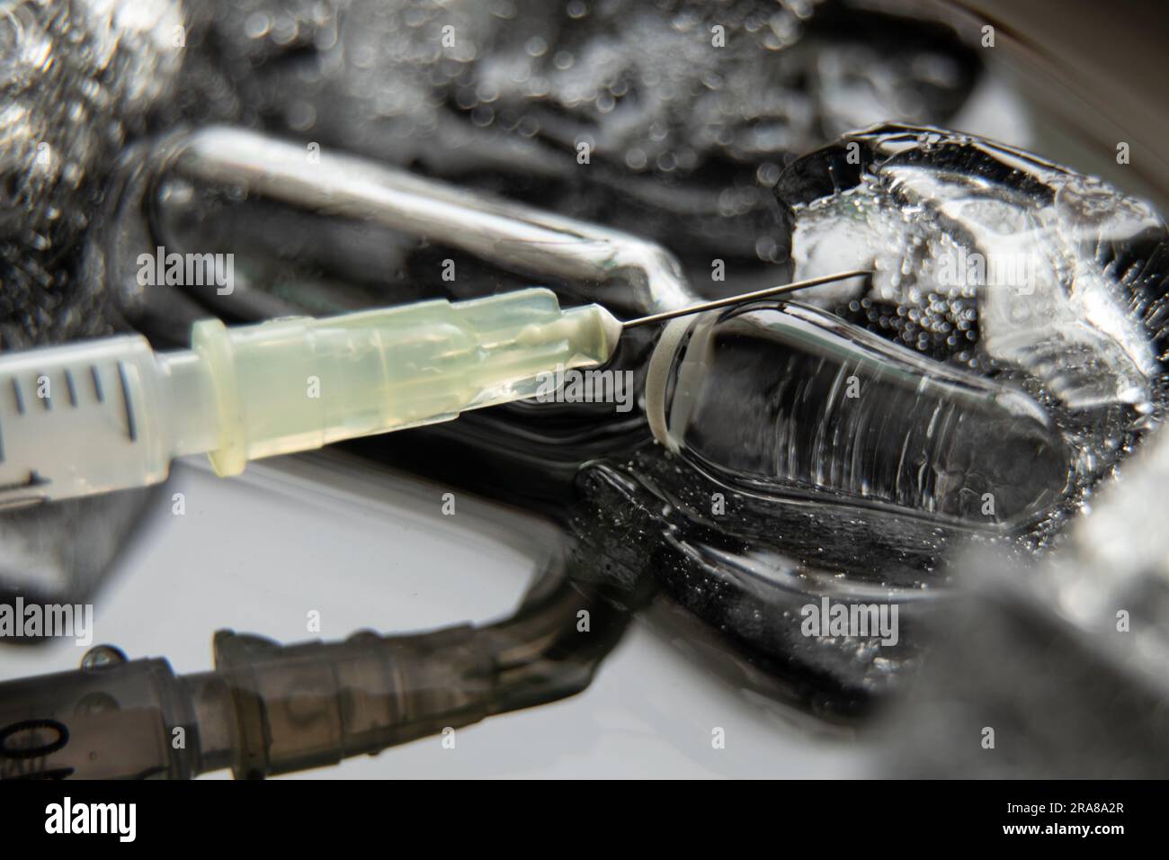 una siringa con un ago e una fiala con un vaccino in ghiaccio, vaccinazione di massa in un panda Foto Stock