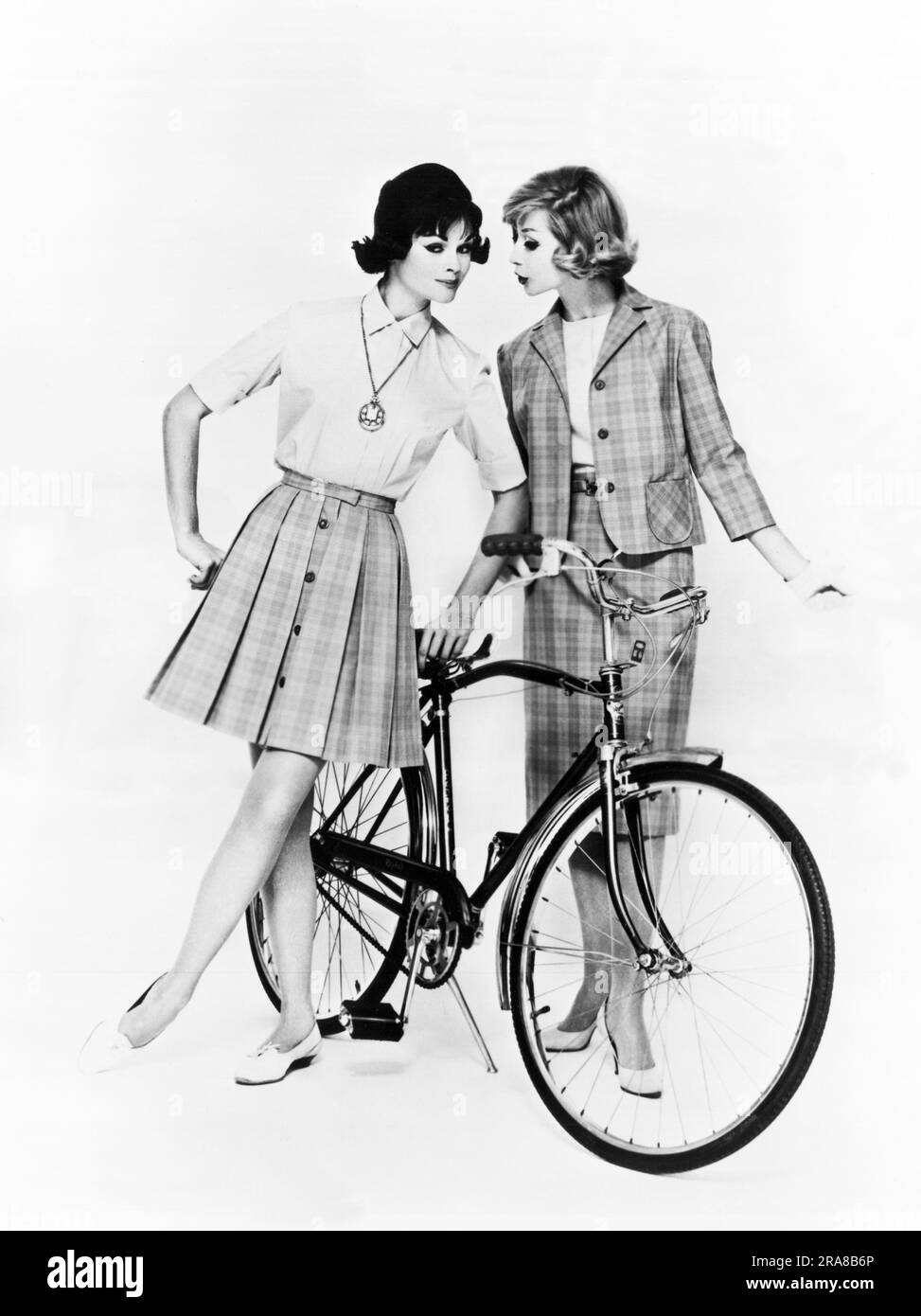 Stati Uniti: c. 1958 due donne con un modello di bicicletta abiti da vacanza in cotone per viaggi o visite turistiche. Sono disegnati dalla signorina Pat della California. Foto Stock