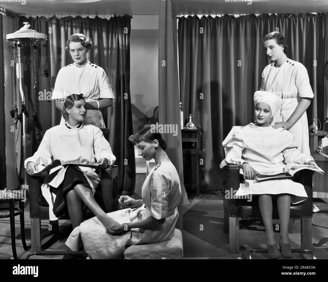 Hollywood, California: c. 1936 due donne in un salone di bellezza si fanno i capelli e le unghie. Foto Stock