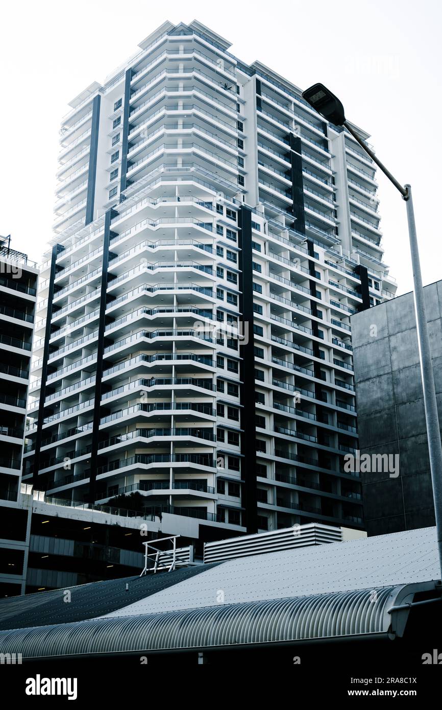 Una fotografia di un tetto in ferro ondulato di vecchia moda in primo piano presenta un contrasto di stile con una moderna e alta struttura sullo sfondo Foto Stock