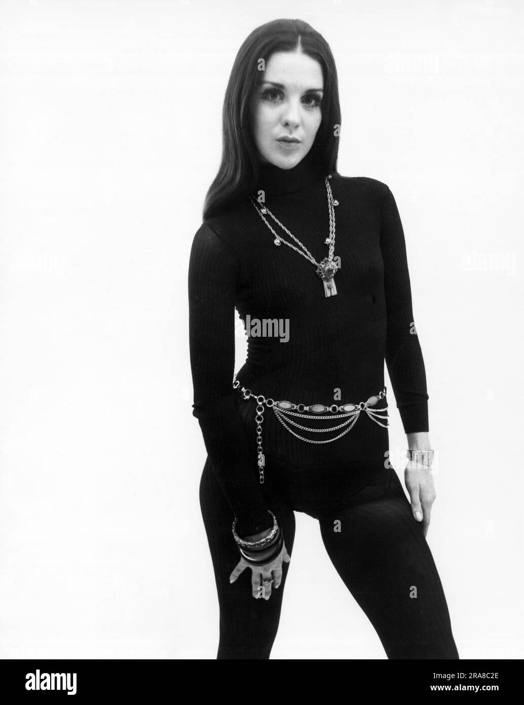 Stati Uniti: c. 1970 Una giovane donna alla moda modella una calza di forma adatta al corpo adornata con una cintura e bracciali. Foto Stock