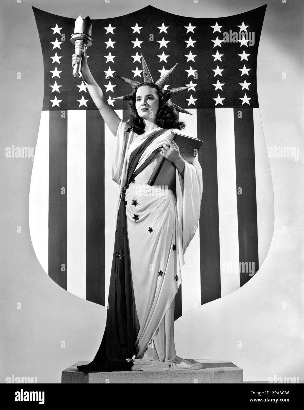 Hollywood, California: 1947 l'attrice Ann Blyth interpreta la Statua della libertà di fronte a una bandiera americana Foto Stock