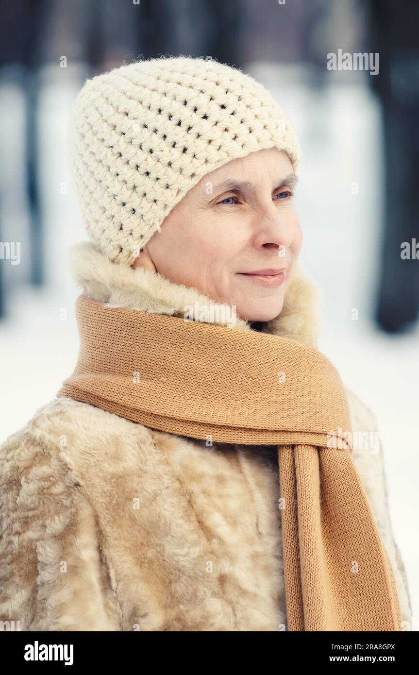 Ritratto di un naturale donna adulta con una sciarpa e un cappello di lana, all'aperto durante la stagione invernale Foto Stock
