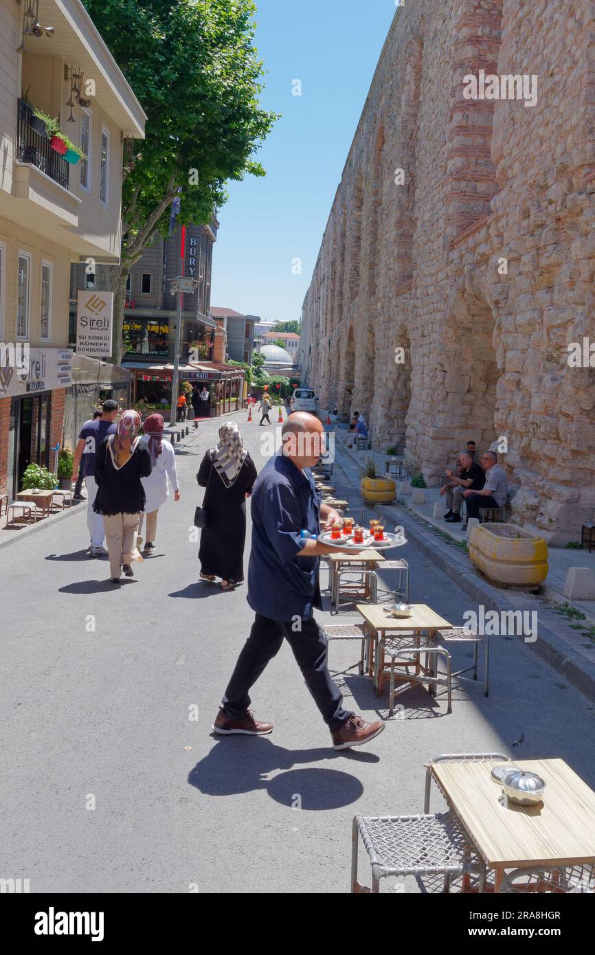 Man serve tè turco in una strada accanto all'Acquedotto di Valente, un Acquedotto romano a Istanbul, Turchia Foto Stock