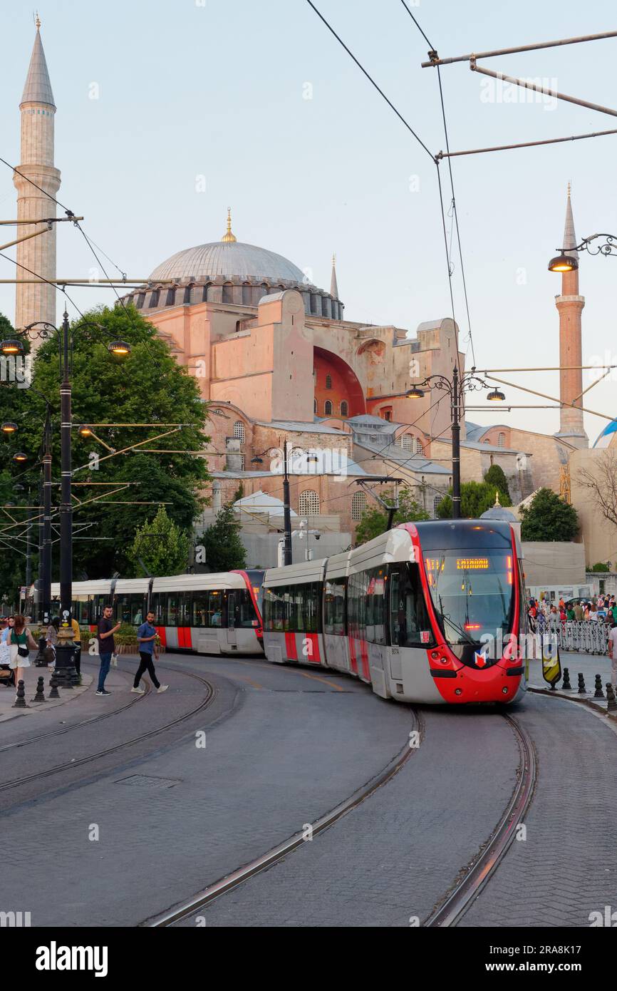 Tram su una strada nel quartiere di Sultanahmet in una serata estiva con la Basilica di Santa Sofia alle spalle, Istanbul, Turchia Foto Stock