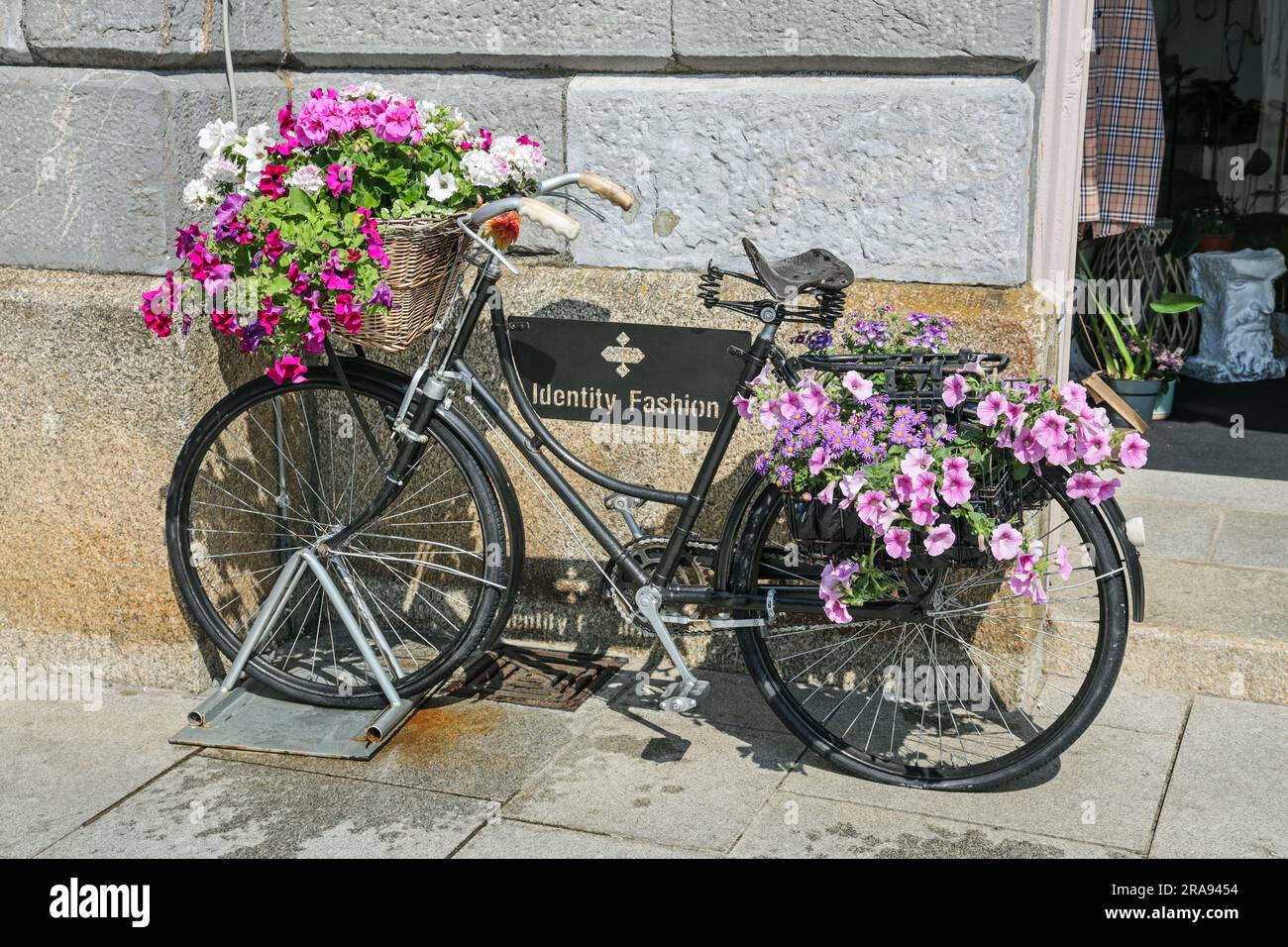 Una bicicletta decorata con flora è un'attrattiva all'esterno di una boutique di moda al Royal William Yard di Plymouth. L'edificio Mills and Bakery Foto Stock