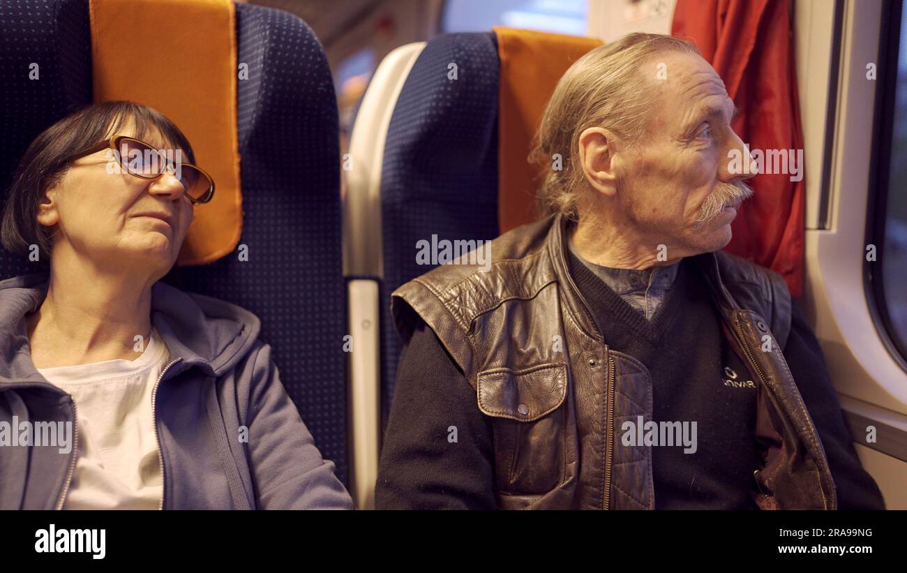Una coppia anziana viaggia in treno, un anziano guarda fuori dalla finestra, una donna che dorme Foto Stock