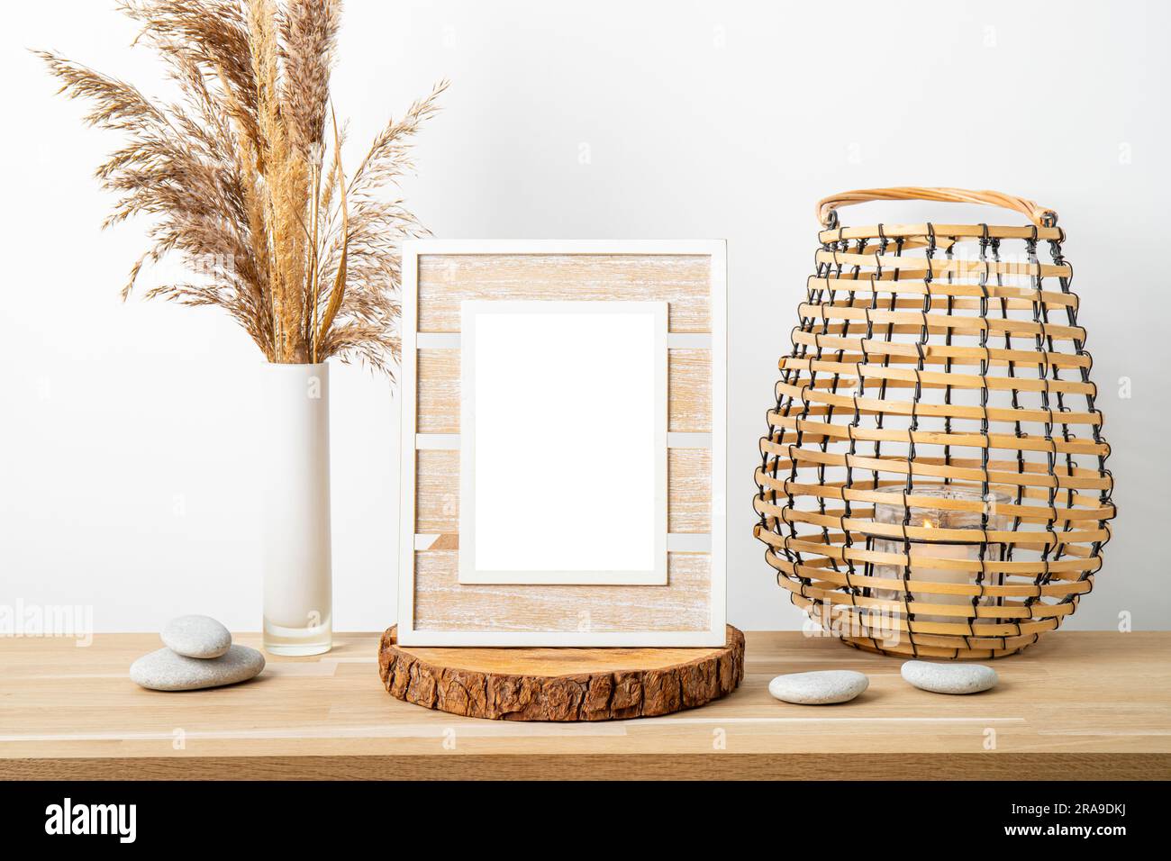 Decorazioni minimali in legno naturale con cornice bianca vuota, canne a secco in vaso e lanterna rotonda in legno a lume di candela. Sfondo interno casa. Foto Stock