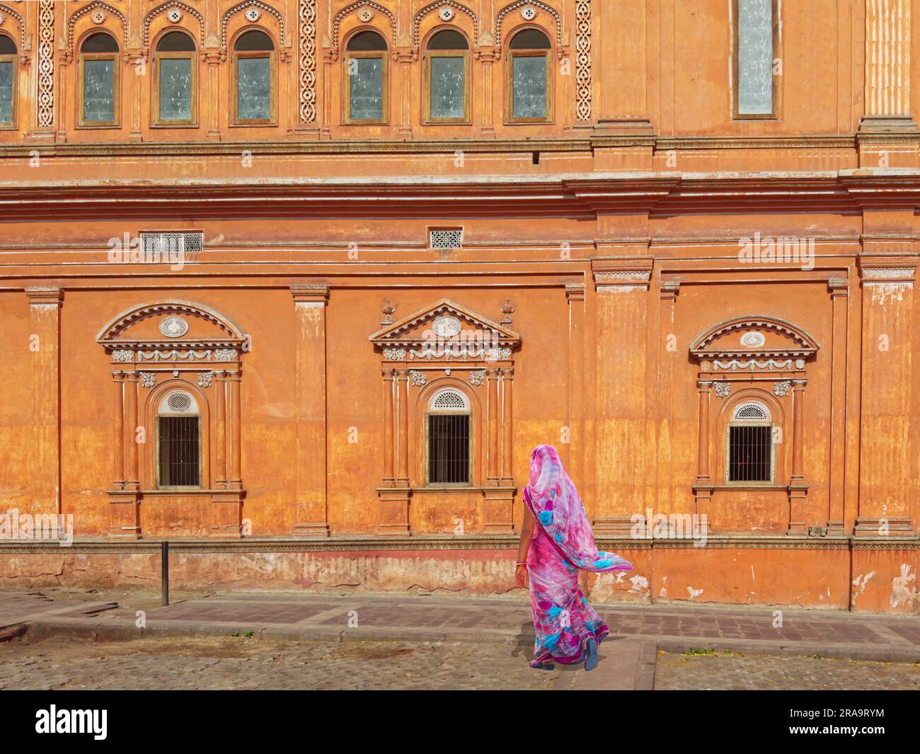 Una donna indiana che indossa un sari colorato cammina davanti a un monumento Foto Stock