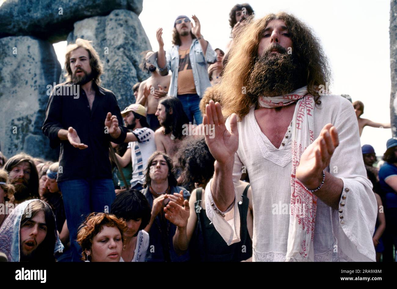 Stonehenge Free Festival solstizio estivo anni '1970 John Pendragon poeta e hippy New age, editore della rivista Tribal Messenger. Folle di hippy si riuniscono all'interno della cerchia ristretta di Stonehenge durante il festival per ascoltare John Pendragon, egli chiama in nome degli antichi dei pagani e riceve la sua poesia. Wiltshire, Inghilterra 21 giugno 1979 70s UK HOMER SYKES Foto Stock