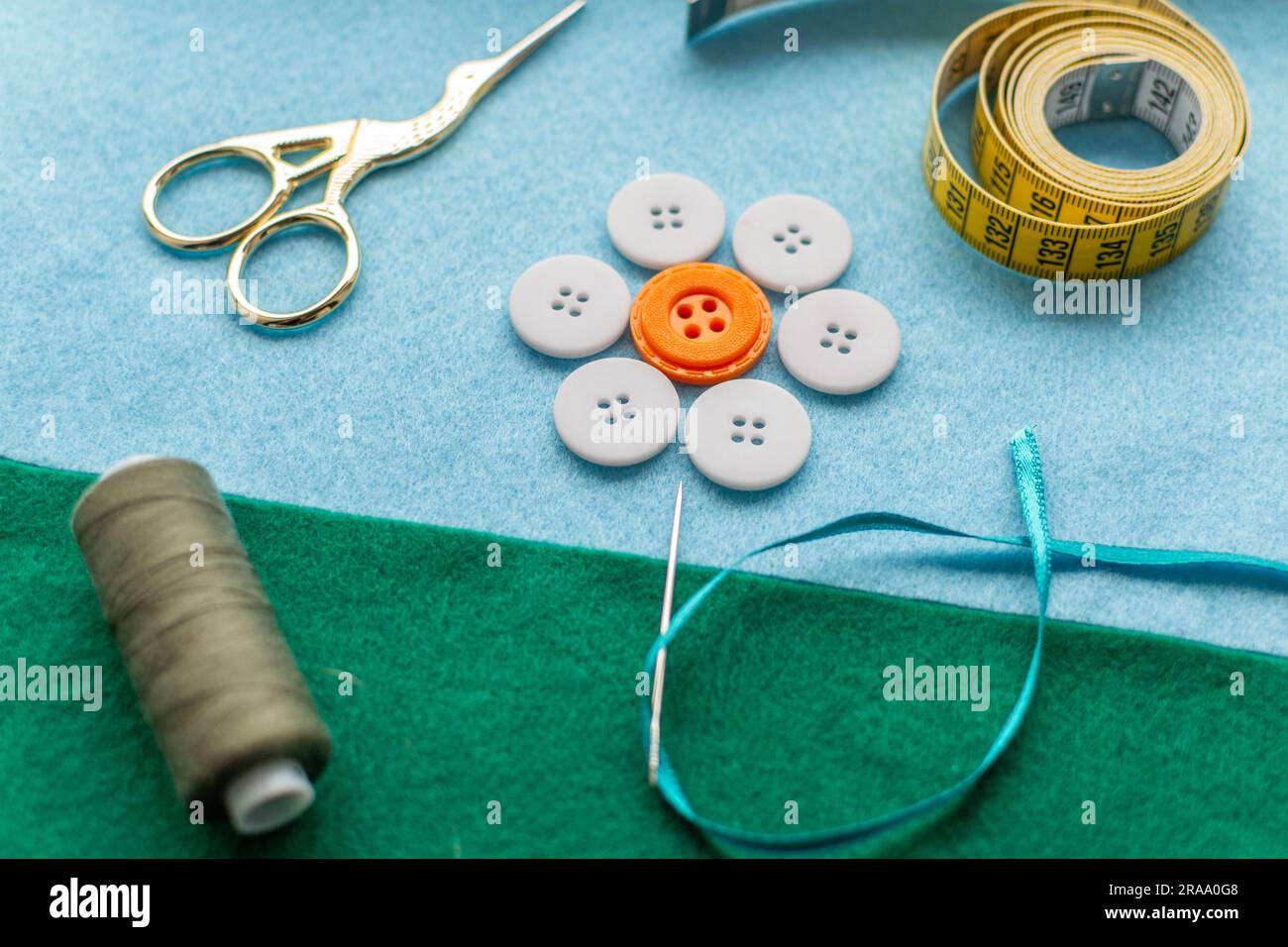 Composizione creativa a tema cucito: Fiore fatto di bottoni, ago su tessuti in feltro. Foto Stock
