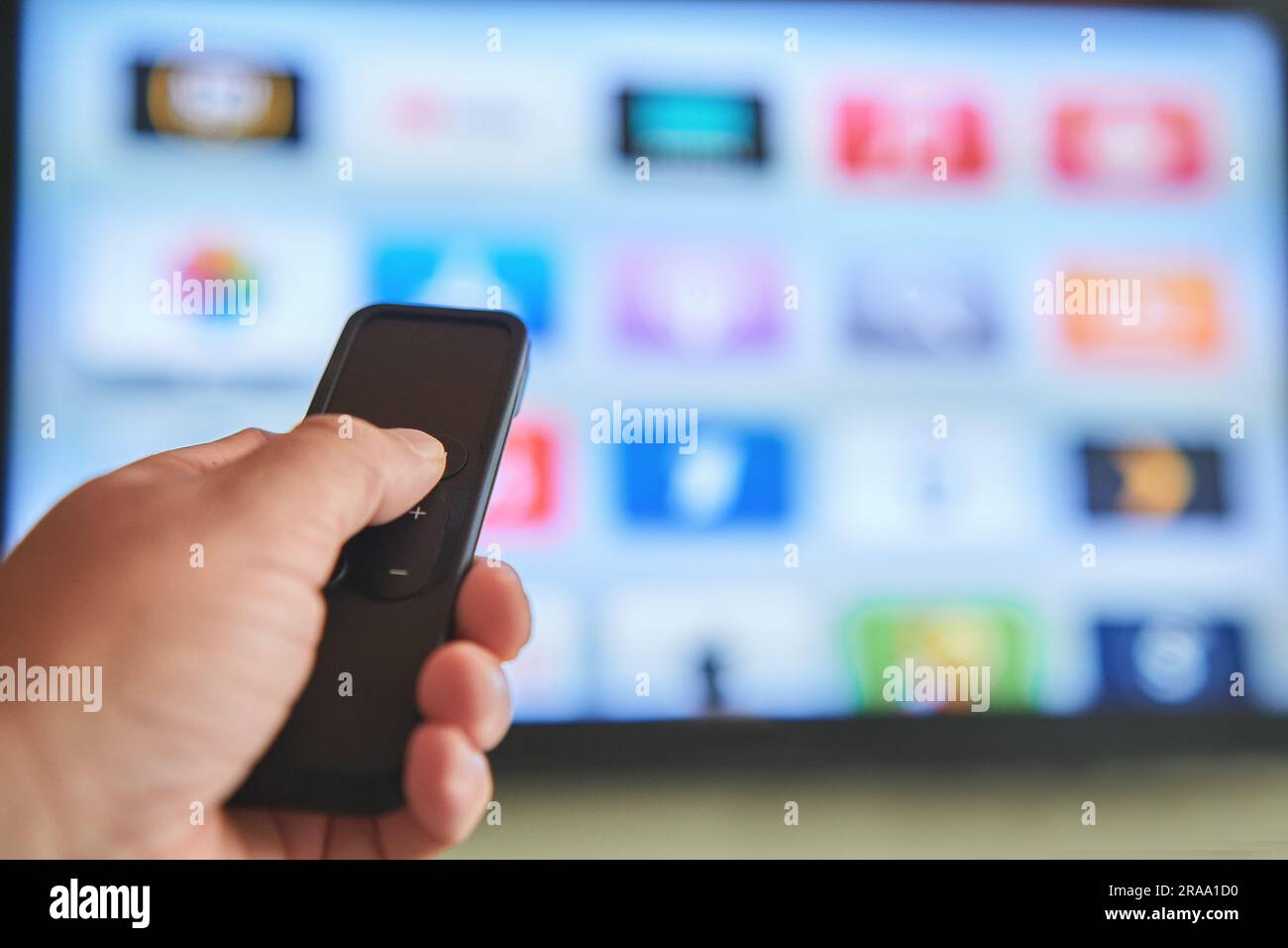Concetto di streaming multimediale. Telecomando con impugnatura. Schermo TV con molte immagini. Foto Stock