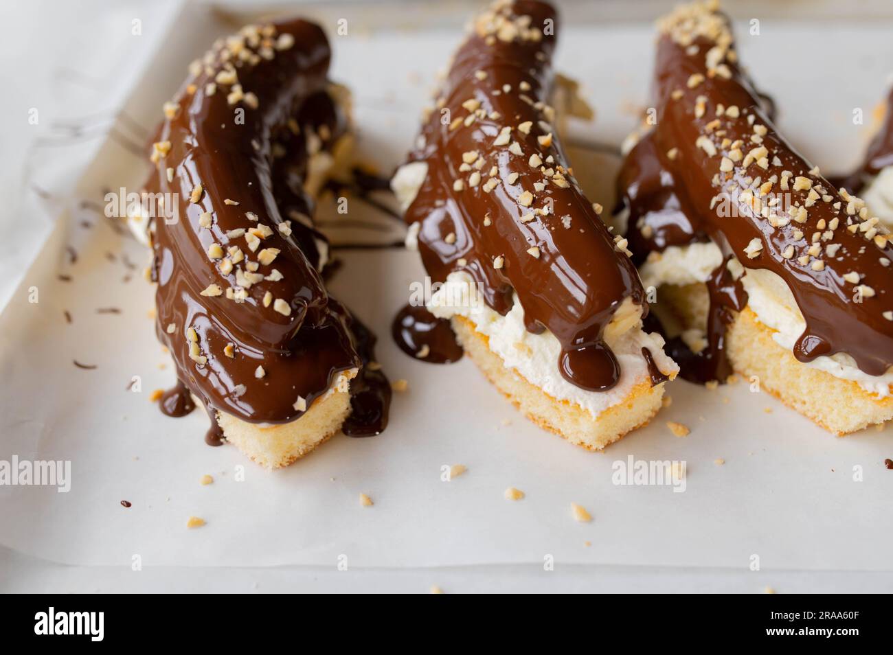 Dessert alla banana con torta di spugna condita con panna montata, banane intere, cioccolato fuso e noci. Foto Stock