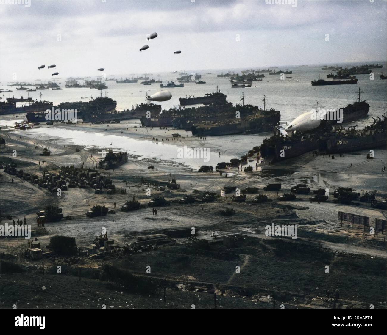 Una splendida foto panoramica di una spiaggia d'invasione francese con le acque del canale spesse di navi militari statunitensi, mentre rinforzi e rifornimenti vengono incanalati a terra dopo la conquista della penisola di Cherbourg. I palloncini di sbarramento proteggono le navi da attacchi nemici. Una mongolfiera rimane ancora sul ponte di un grande veicolo di atterraggio. Camion pieni di rifornimenti e truppe si dirigono verso l'interno attraverso la spiaggia. Il D-Day iniziò il 6 giugno 1944 alle 6:30 e fu condotto in due fasi d'assalto û allo sbarco aereo delle truppe alleate seguito da un assalto anfibio della fanteria. Gli sbarchi in Normandia lo erano Foto Stock