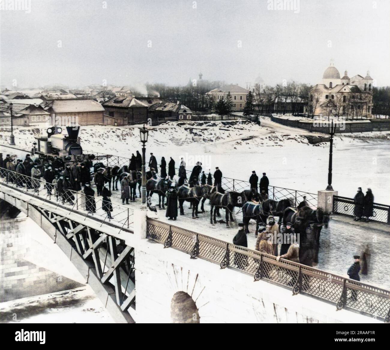 Vista di un ponte al di sopra del quale un locomotore è trainato da cavalli di quattordici per essere consegnato alla linea Orlovsko-Kitebskaya. Una folla di persone si sono riunite nella neve a guardare passare. Data: 1867 Foto Stock