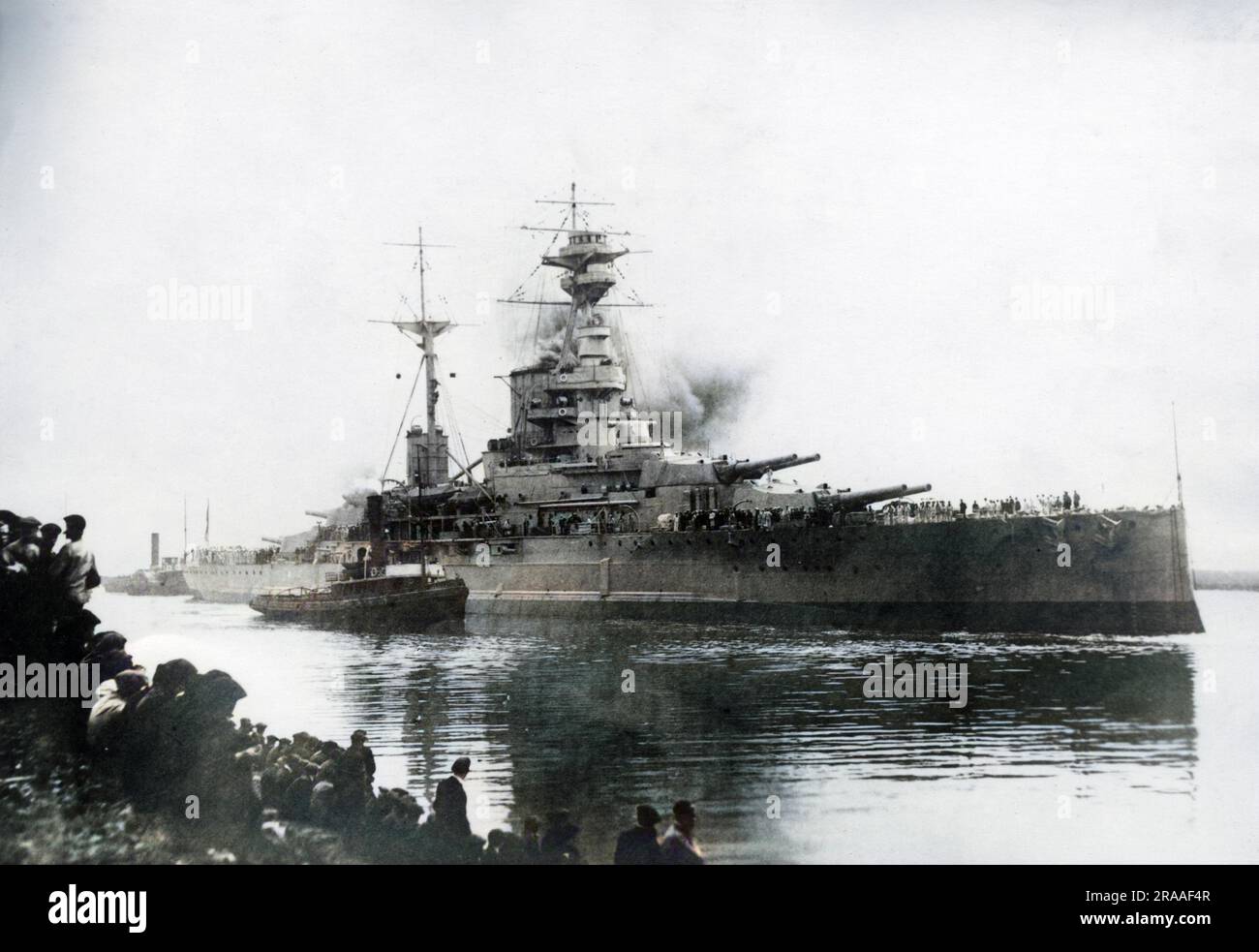 HMS Royal Sovereign, nave da battaglia della classe British Revenge, varata nel 1915, servì nella prima guerra mondiale e parte della seconda guerra mondiale. Visto qui con un rimorchiatore accanto, e gente che guarda dalla terra. Data: XX secolo Foto Stock