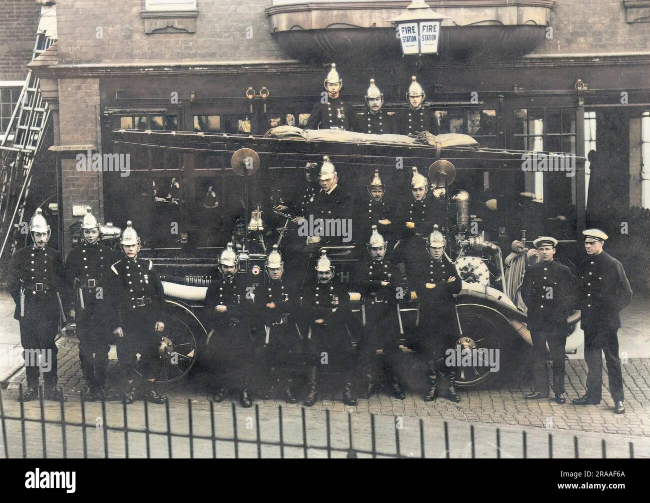 Vigili del fuoco e motore dei pompieri in posa fuori da una caserma dei pompieri. Data: Circa 1905 Foto Stock