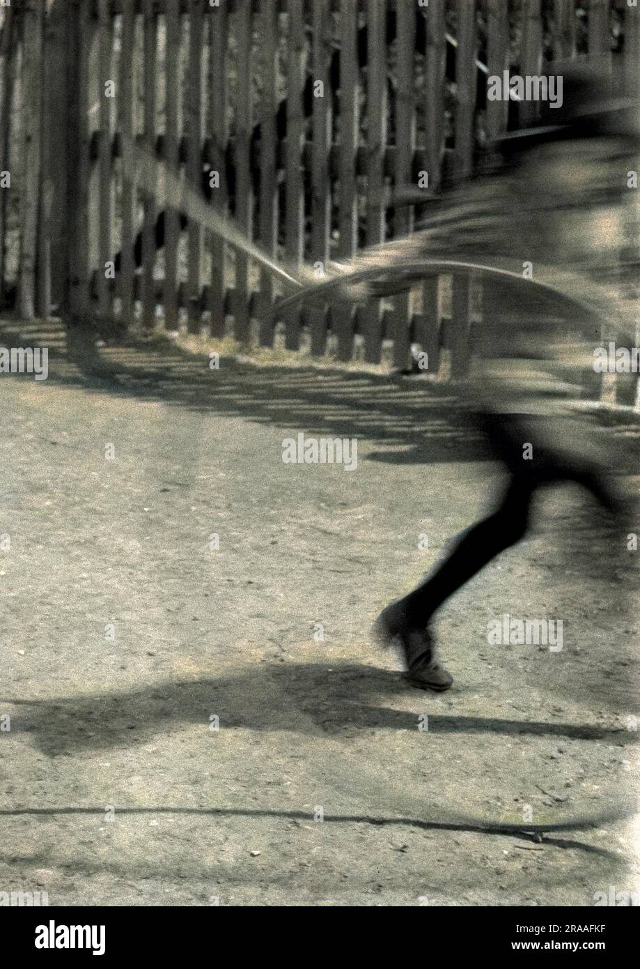 Un'immagine sfocata di un bambino che gioca con un cerchio e bastone -- evidentemente muovendosi avanti a velocità! Foto Stock