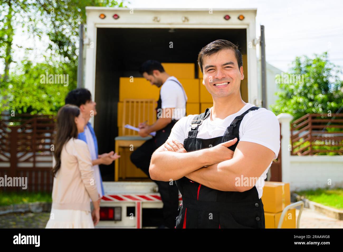 Ritratto sorridente dell'addetto alla consegna presso la sede dei clienti, dei clienti che ricevono la scatola dal corriere, degli addetti alla consegna soddisfatti che controllano l'ordine e lavorano con loro Foto Stock
