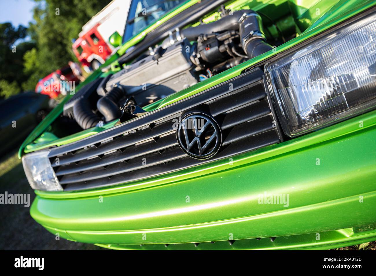 Berlino, Germania - 24 giugno 2023: Logo Volkswagen su un'auto Volkswagen verde su un prato. Foto Stock