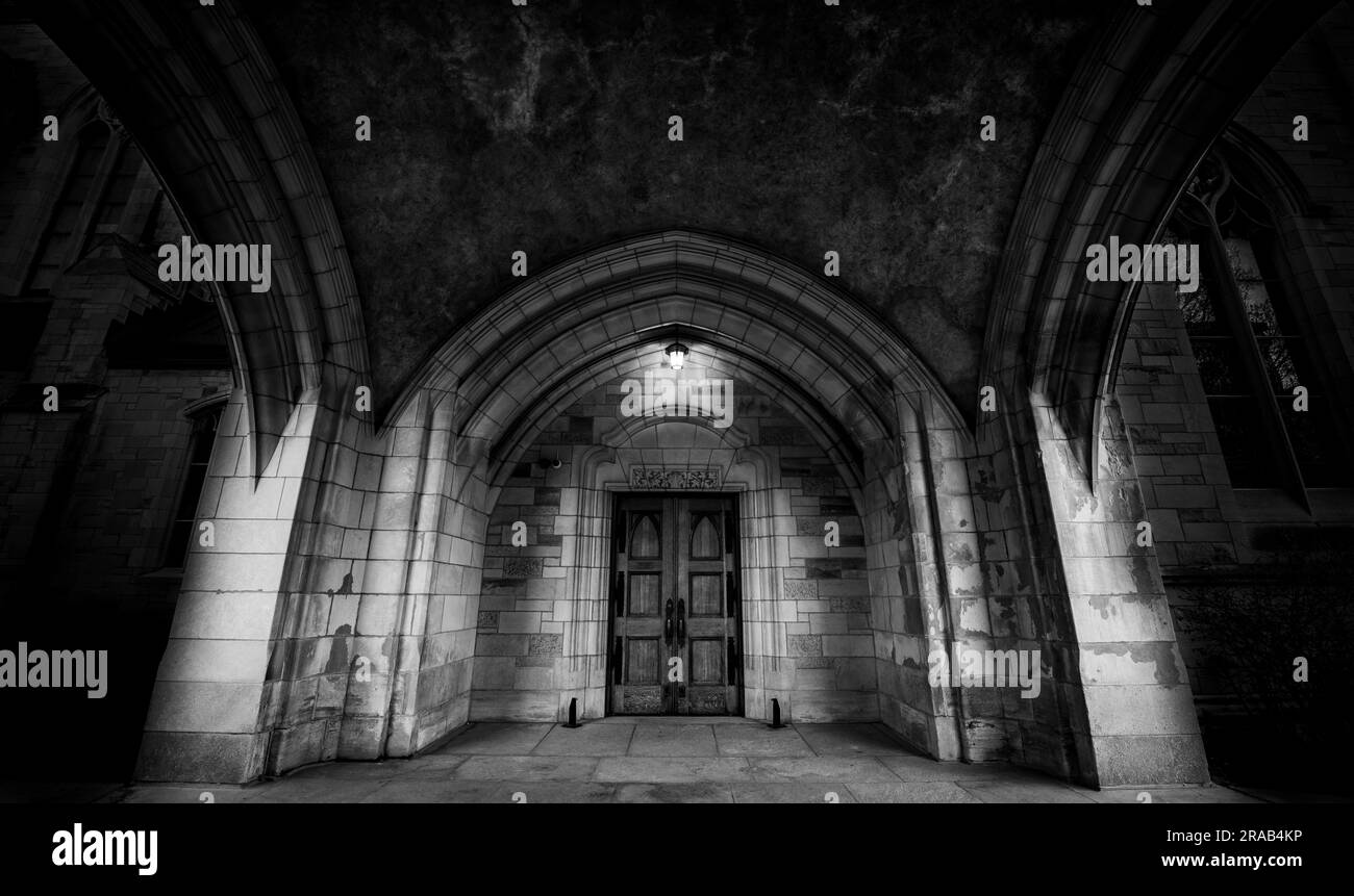 Foto drammatica della porta di St. Chiesa di Andrew a Montreal sotto un tetto in pietra ad arco, con una luce sopra la porta. Foto Stock