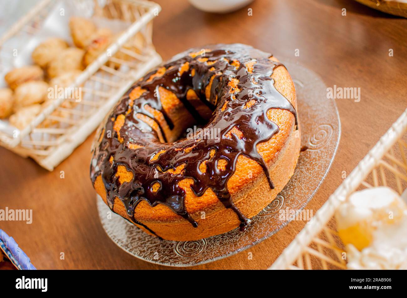 Foto di torta alla vaniglia con glassa al cioccolato disposta su un tavolo. Tavolo con omaggi. Foto Stock